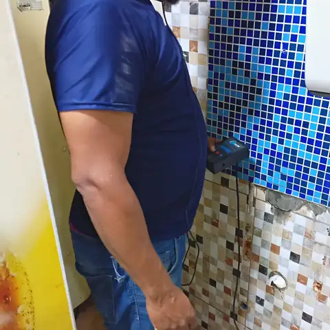 Geofone apoiado na parede de pastilhas do banheiro para ouvir a água no cano embutido